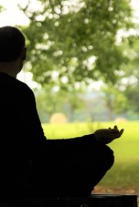 Un homme, de dos, méditant sous les arbres